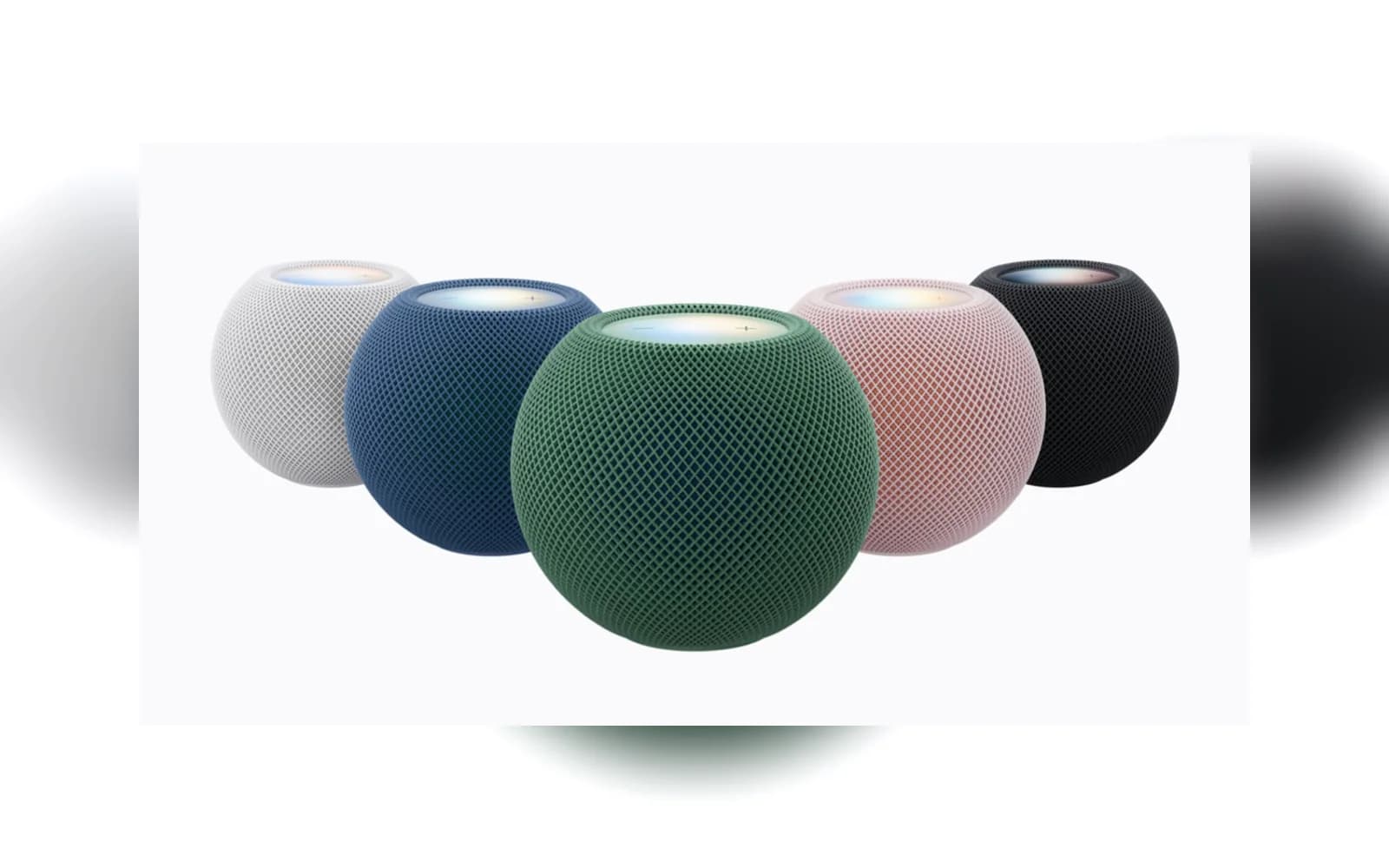 Five round mesh-covered speakers in white, blue, green, pink, and black, with the green speaker centered in front.